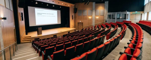 Auditorium luxembourgeois à gradins avec sièges rouges et écran géant, configuration pour séminaire d'entreprise